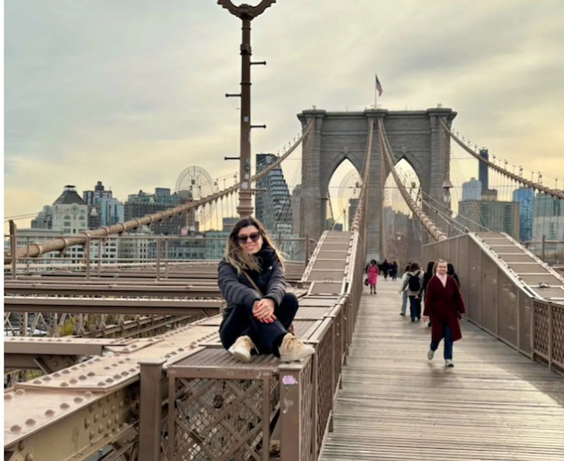 Camila na Brooklyn Bridge, em Nova York, com os prédios de Manhattan ao fundo